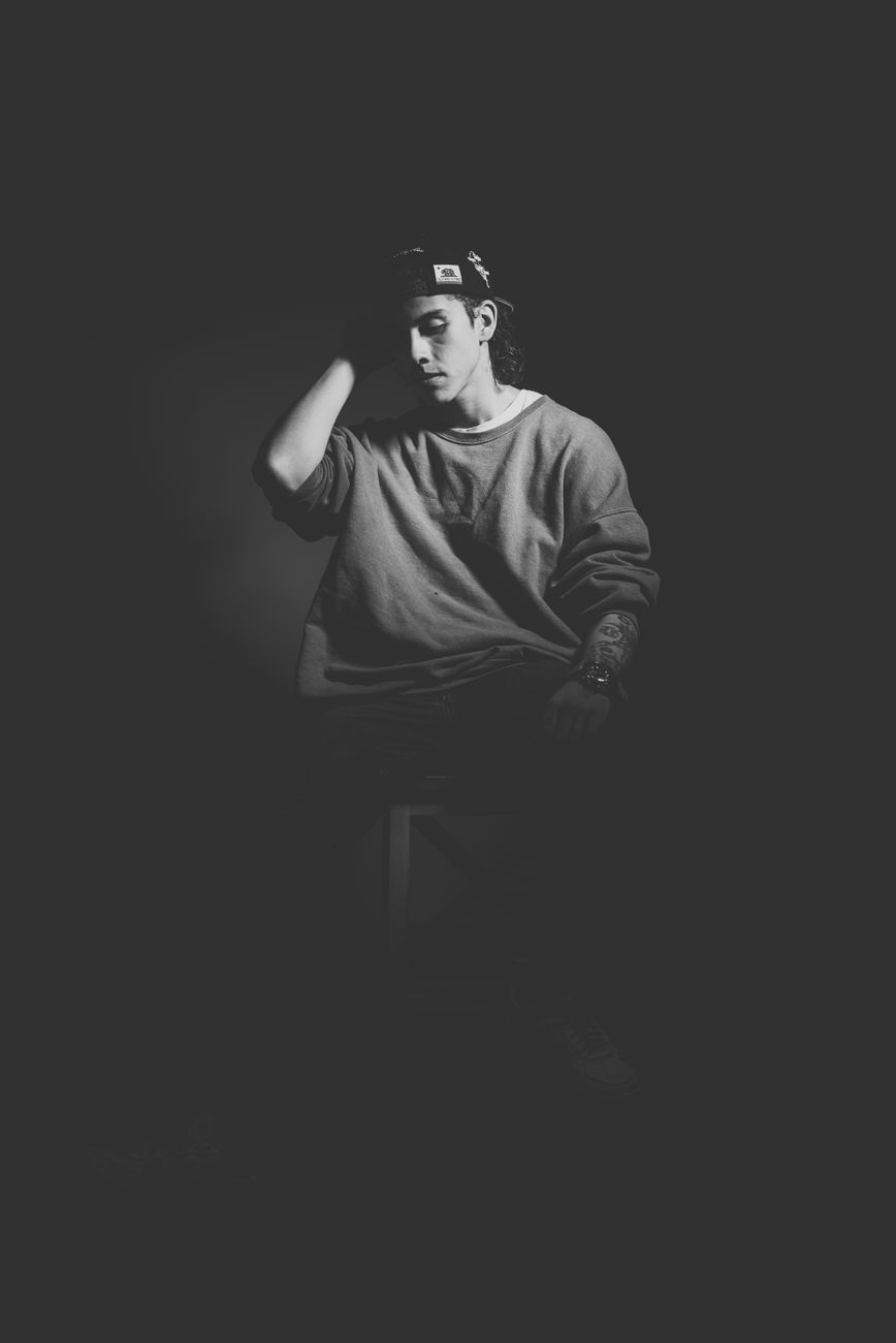 Schwarz-weiß Porträt eines Mannes im Studio, mit Mütze und Pullover